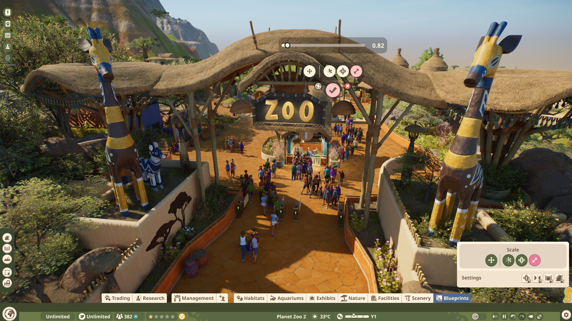 Guests streaming through a thatched zoo entrance while a scenery piece is resized using the scale tool