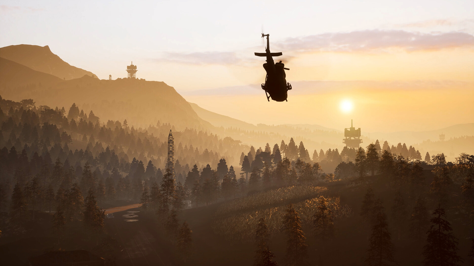 A WARDOGS helicopter silhouetted against a hazy low sun above forested ridges dotted with radio masts
