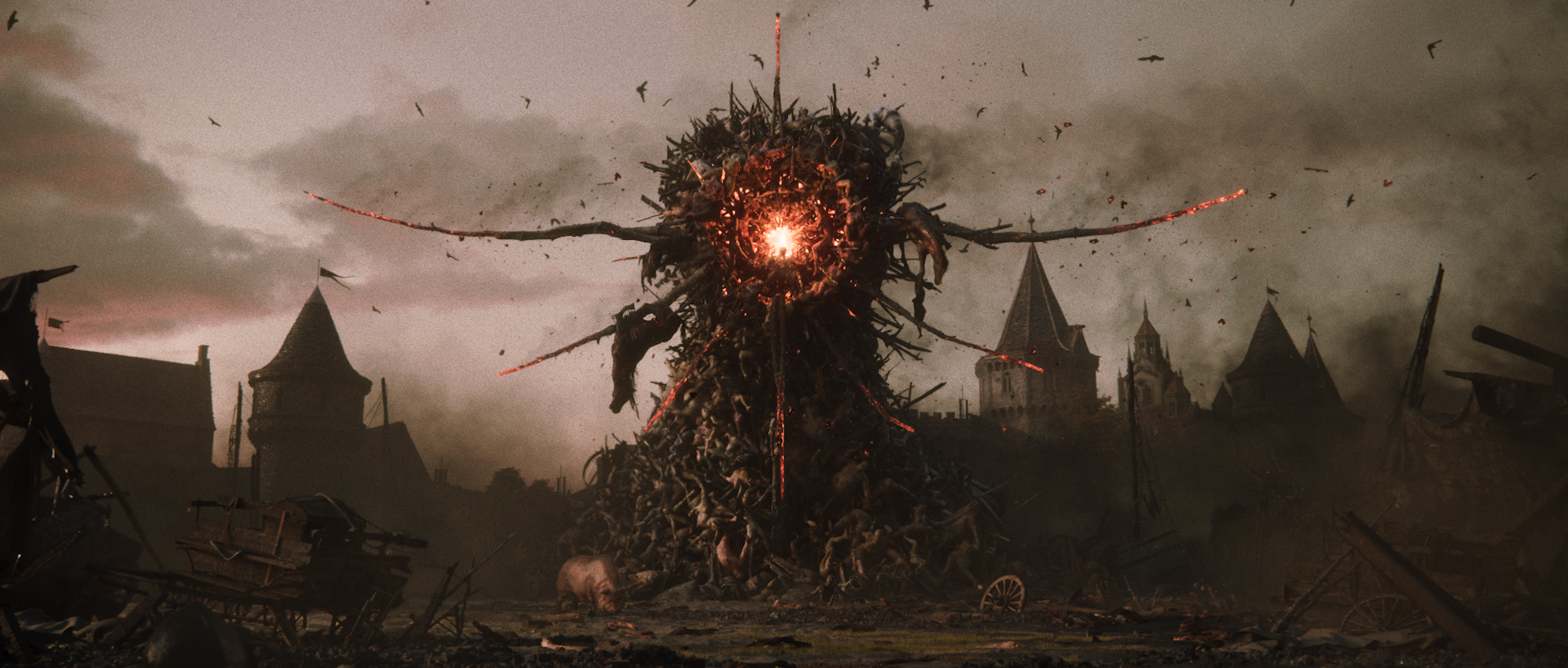 Trailer still of the fused body form looming over the ruined village at dawn