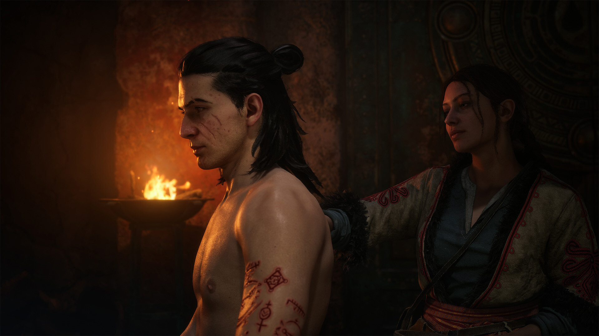 Fresh runes cut into a young man chest and shoulder beside a fire, a woman in embroidered dress standing behind him