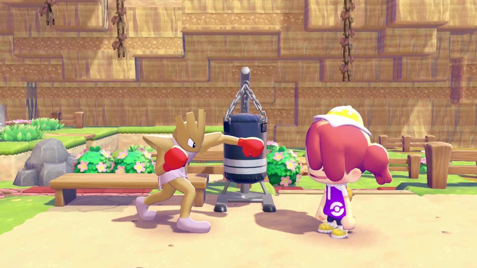 Hitmonchan training at a punching bag while the player watches in a sandy training area