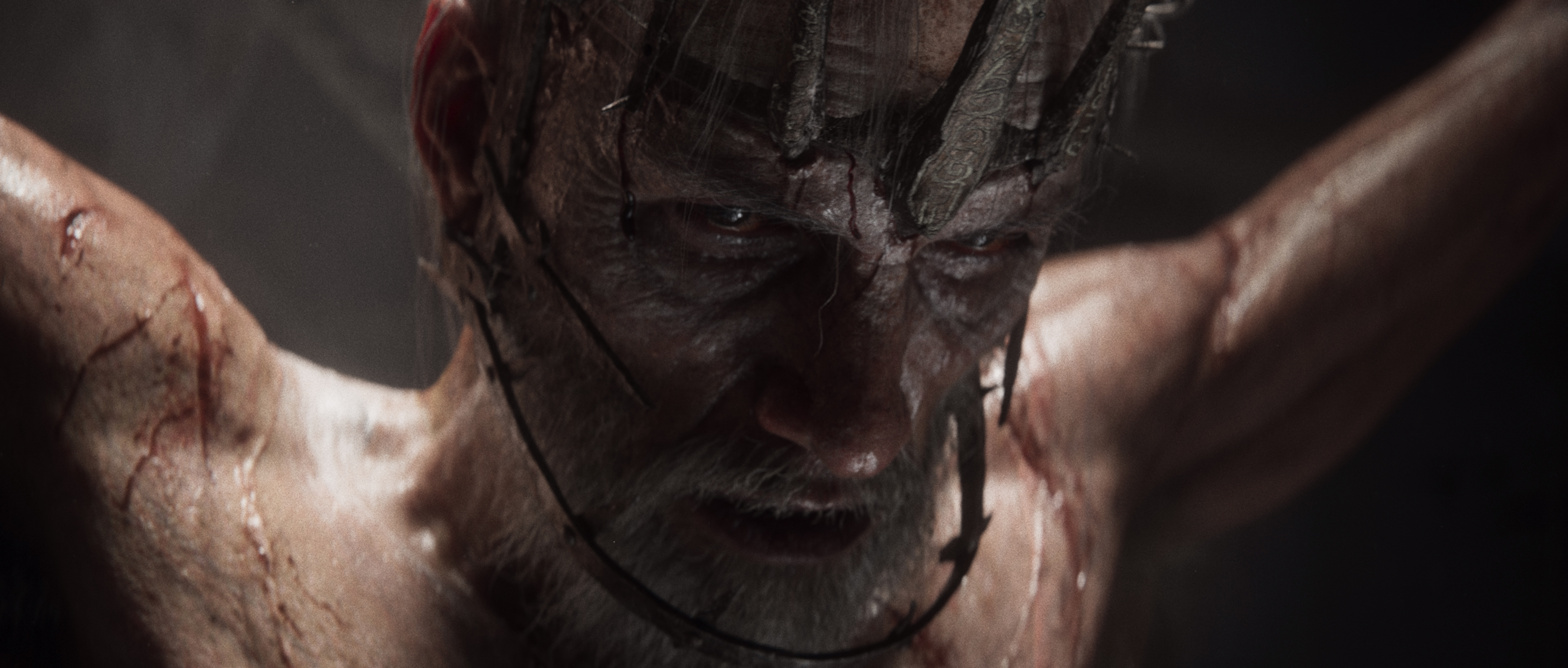 Trailer still of the bound older man at the centre of the ritual, wearing a crown of thorned branches