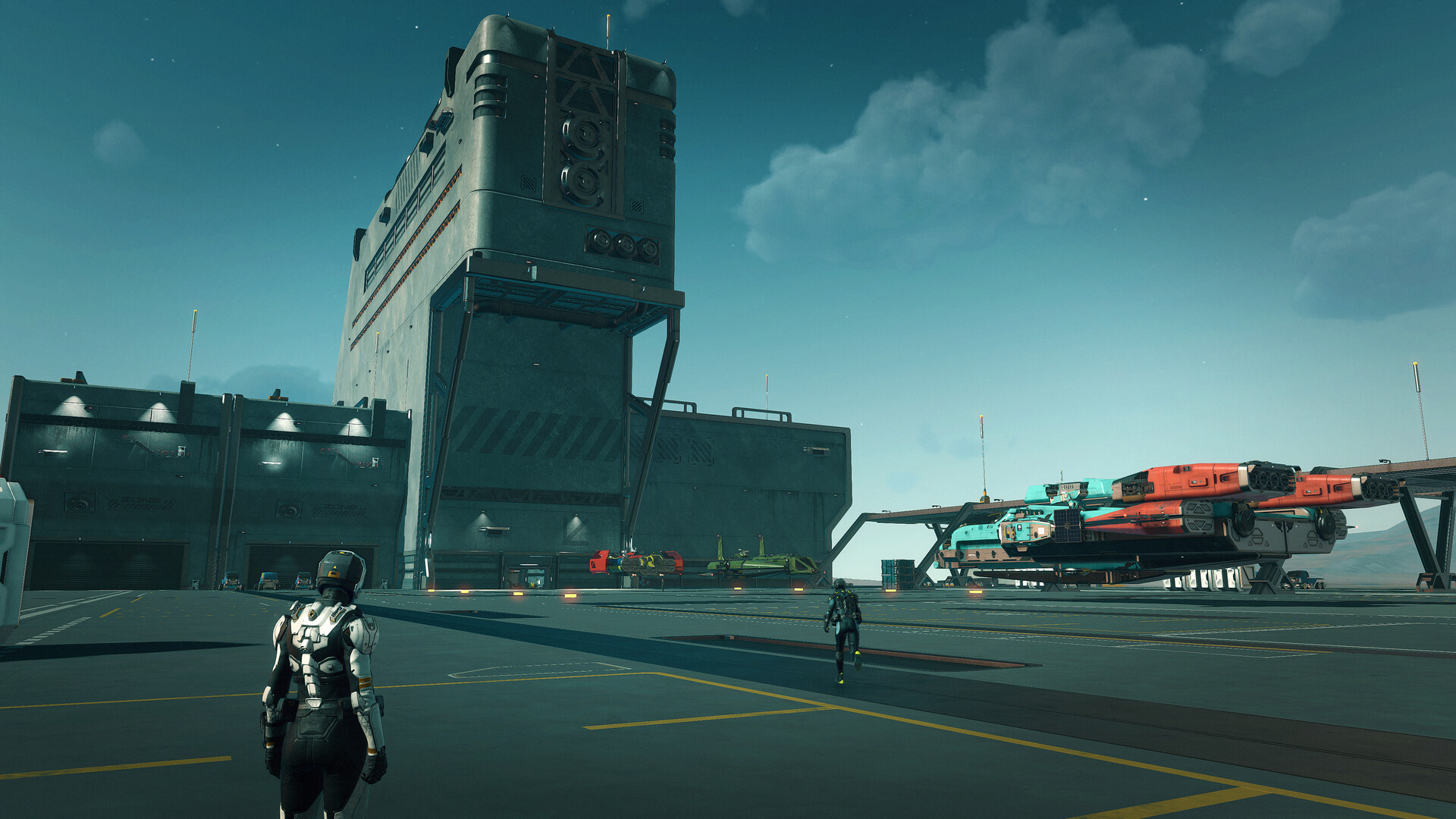 A planetside spaceport under a blue sky, with two suited figures on the landing apron, a control tower, hangar bays, and ships parked on raised landing cradles