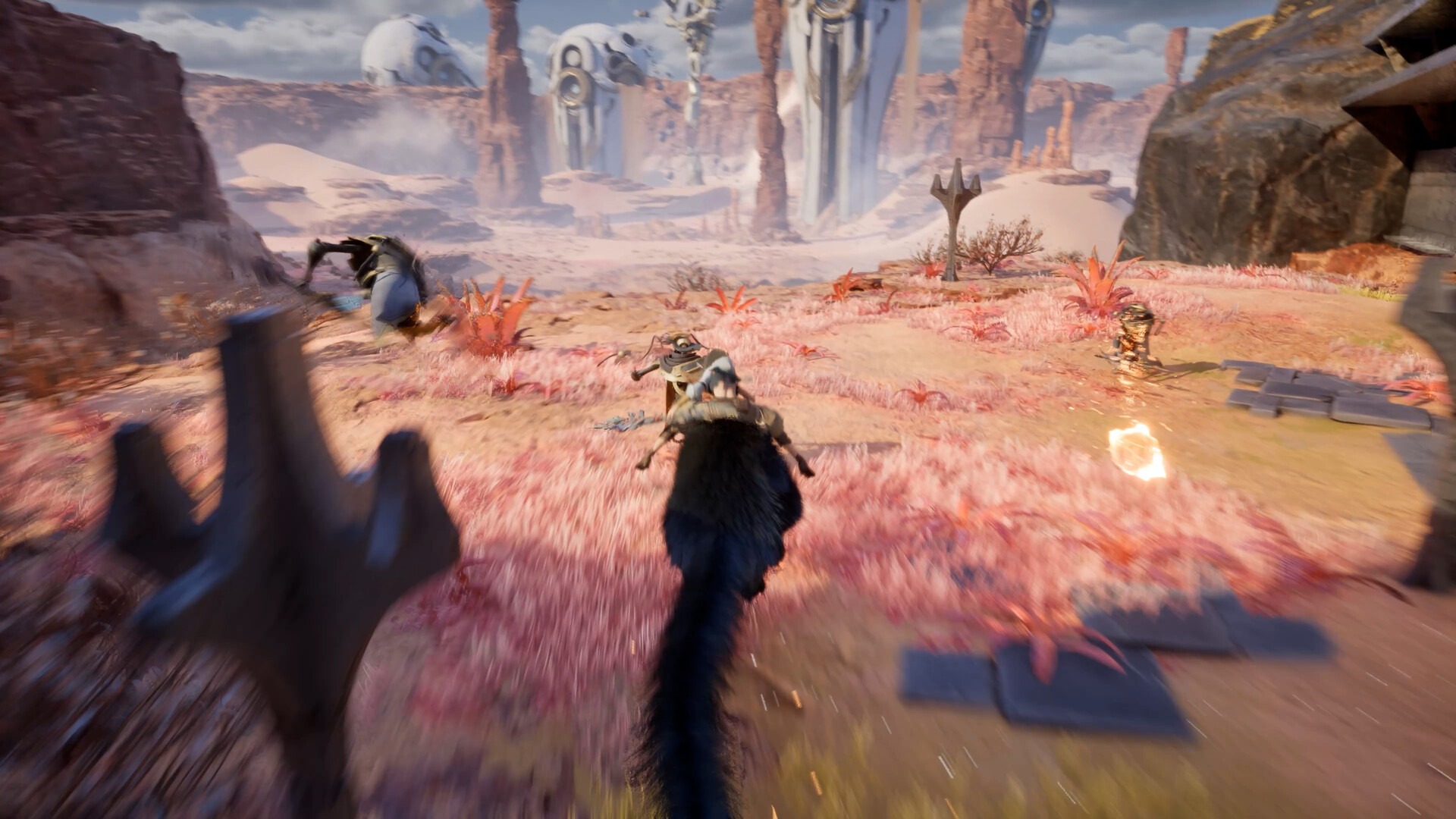 Third-person chase across a pink-grassed desert as the large dark cat runs toward armoured enemies, with colossal pale skeletal figures standing on the horizon