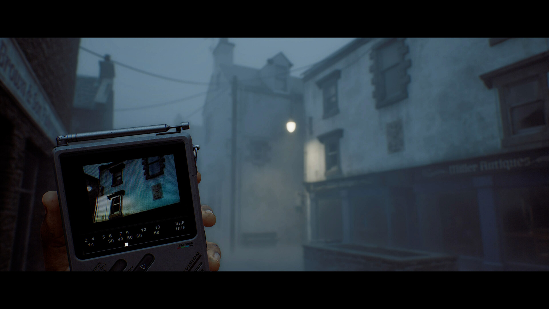 The CRTV held up in a fogbound street, its screen showing a building