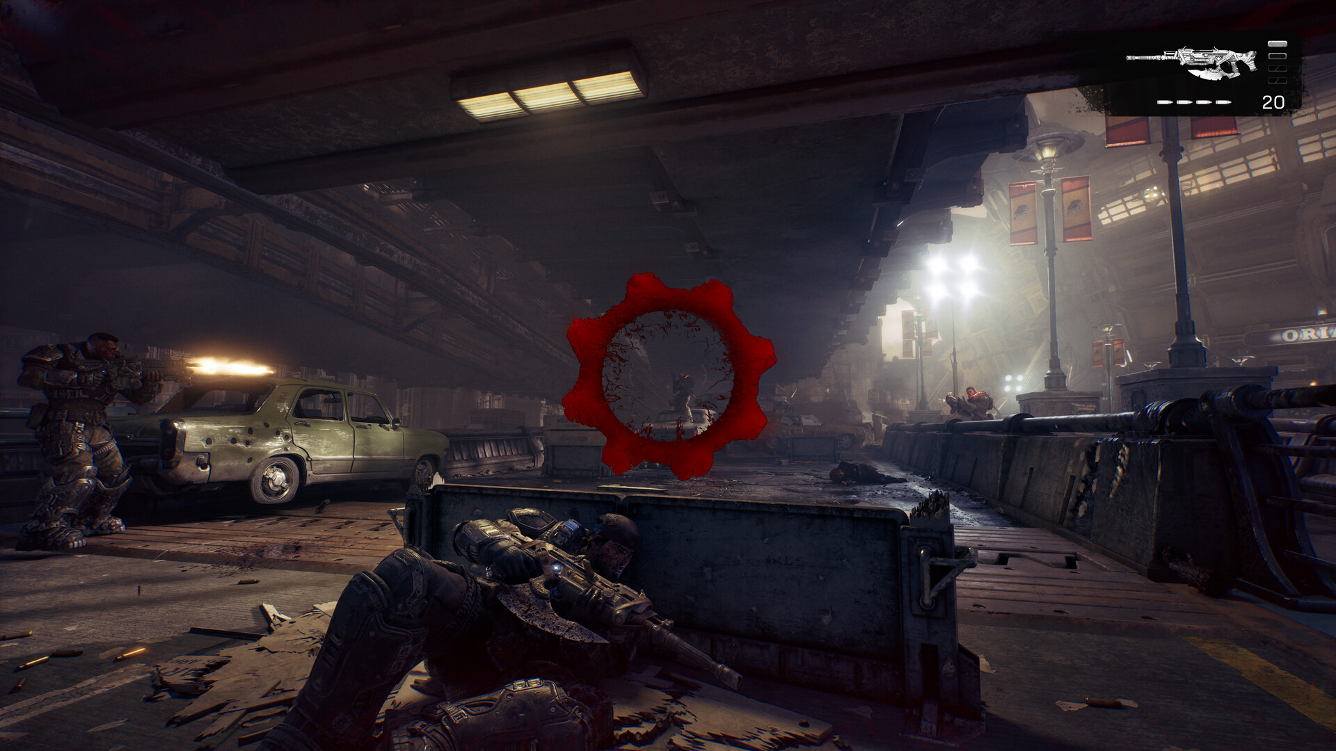 A Gear lies prone behind a low concrete barrier under an overpass while a squadmate fires from behind a wrecked car