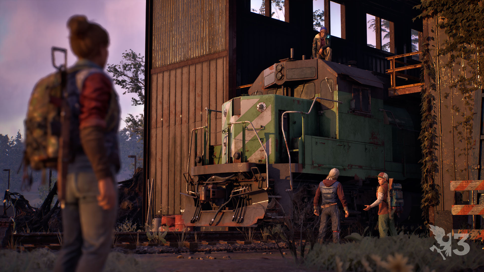 Four survivors gather around a green diesel switcher locomotive parked inside an open timber engine shed at sunset, one of them standing on the roof of the cab.