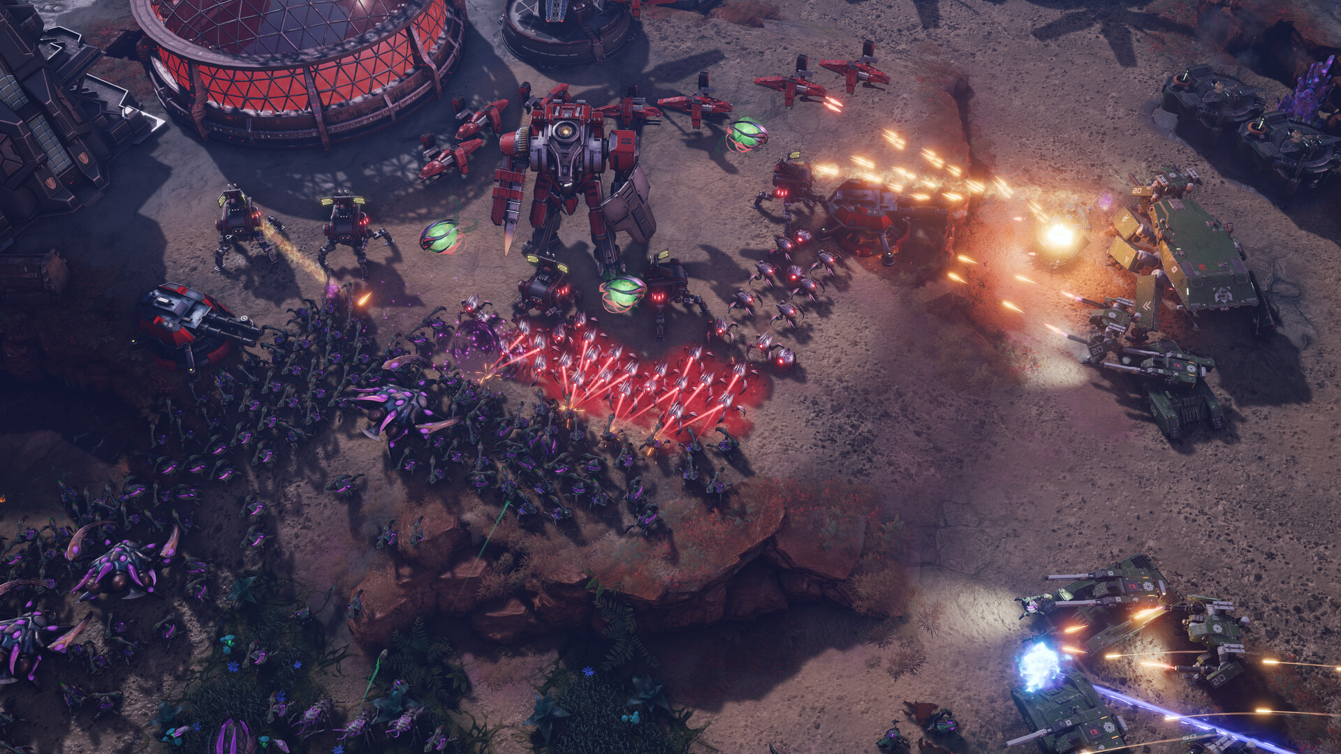 Three-way engagement on open ground: a red-team battlemech and gunships, a purple insectoid swarm and a green-team armoured column trading fire beside a domed structure